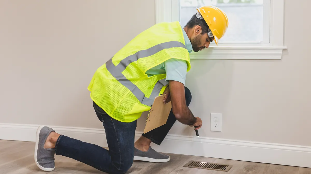 Home inspector checking outlet and floor vent in a room