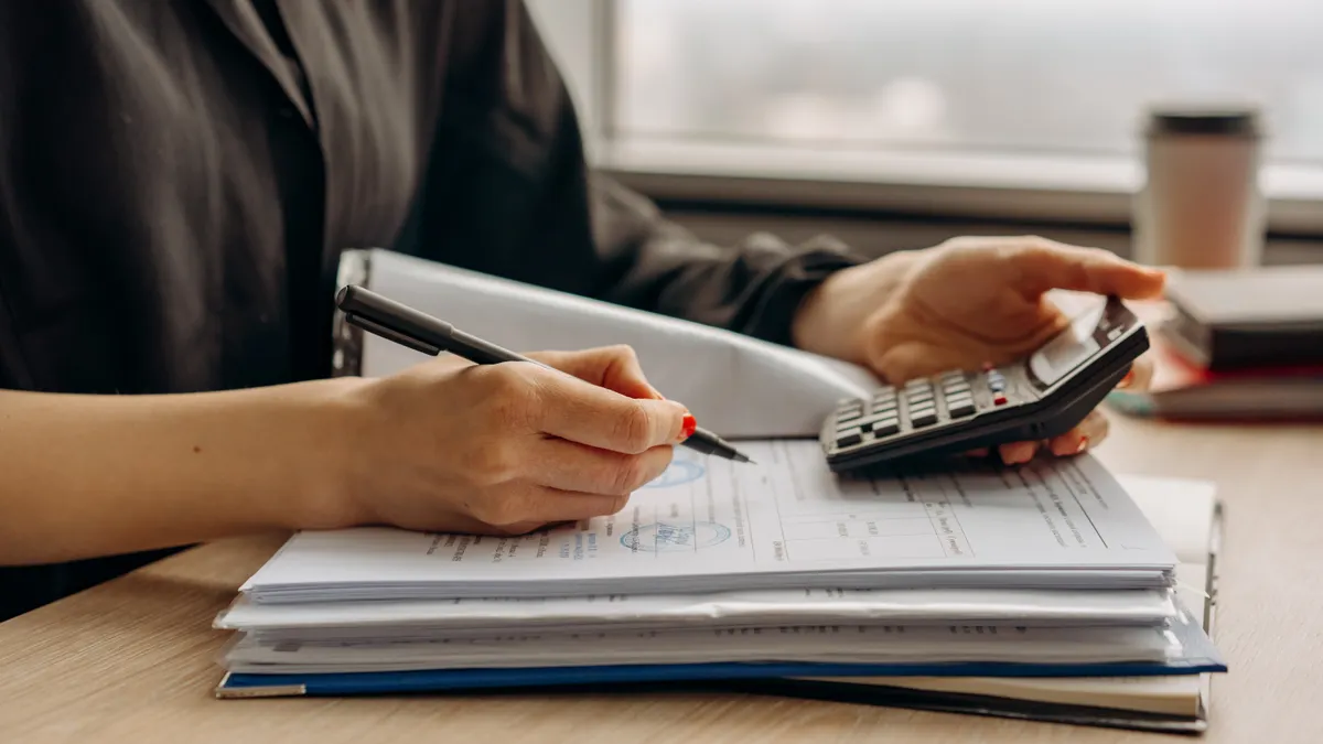 Financing and budgets for first flips — The Complete Guide Person using a calculator while writing on paperwork
