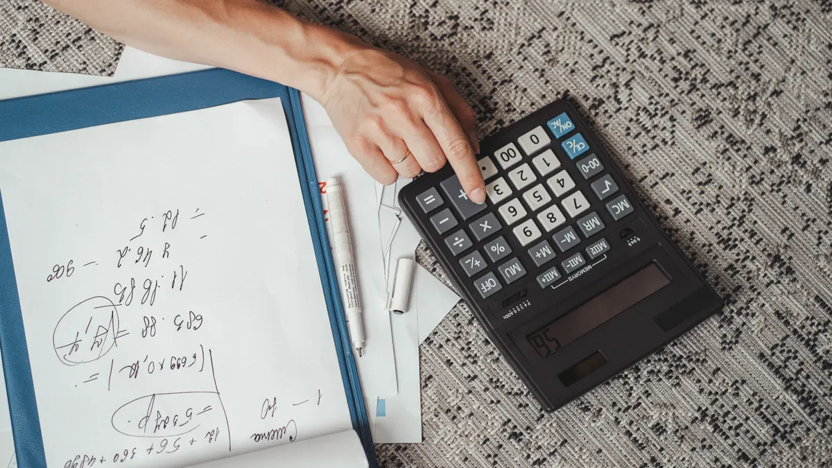Calculator beside handwritten notes and papers