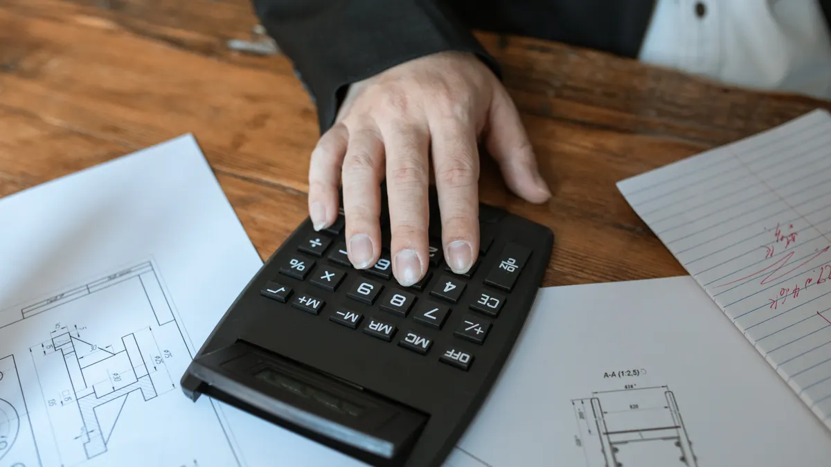 Hand using calculator over floor plans