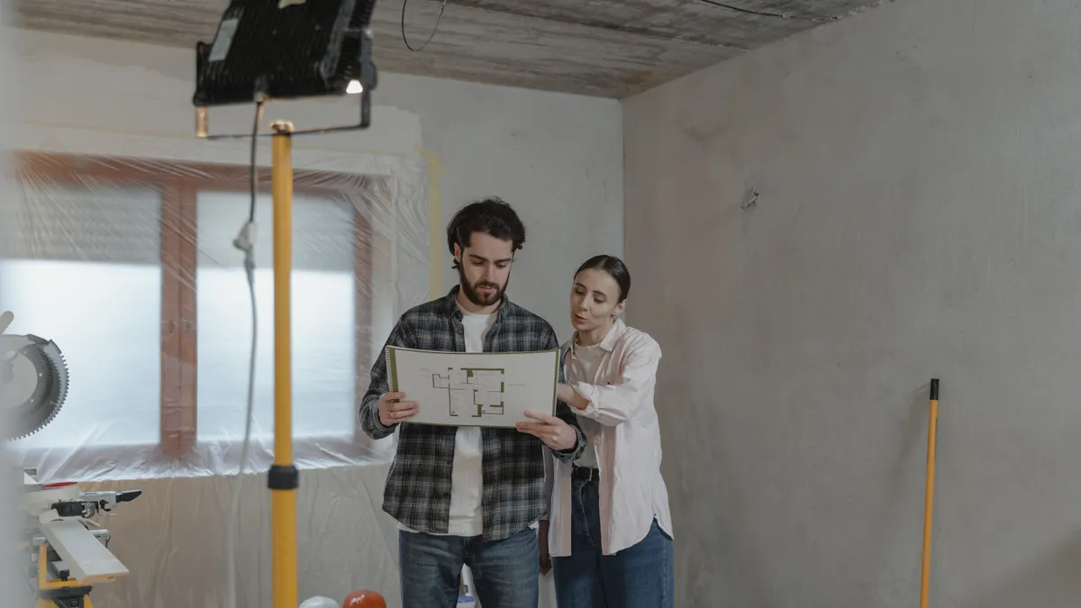 How to Estimate Repair Costs on a House Flip Two people reviewing a floor plan on site