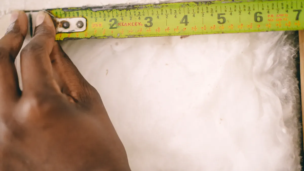 How to Estimate Repair Costs on a House Flip Hand measuring a wall with a tape measure